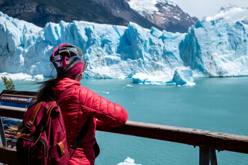 Mujer admirando el Glaciar Perito Moreno desde las pasarelas del Parque Nacional los Glaciares, en Argentina - obrazy, fototapety, plakaty