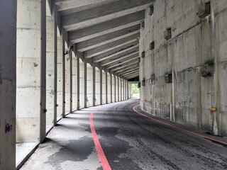 Fototapeta premium Taroko, Taiwan - 11.26.2022: Concrete section of Swallow Grotto Trail with a highway passing through concrete ceiling and pillars in the Swallow Grotto Gorge before 403 earthquake during the pandemic