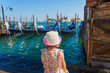 Little girl is watching the gondolas of the Grand Canal on a sunny day in Venice, Italy. San...