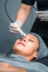 Naklejka premium therapist doing cavitation operation asian woman for wrinkles fat removal. clinic doctor using cavitation equipment to remove wrinkles on woman skin. female patient get cavitation on skin by surgeon