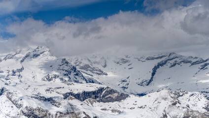 Fototapeta na wymiar Monte Rosa snowy slopes engulfed by clouds in Sesia valley, Italy