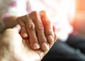 Caregiver, carer hand holding elder hand in hospice care background. Philanthropy kindness to...