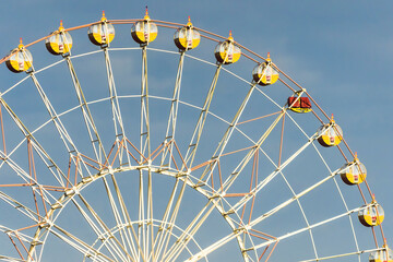 Ferris wheel in the amusement park against the background of the summer sky