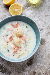 Green bowl with scallop chowder on a light-brown granite background, vertical shot, high angle view