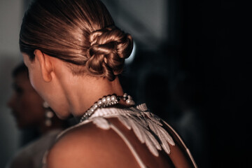 Back view of women's elegant evening hairstyle with hair gathered in a bun.