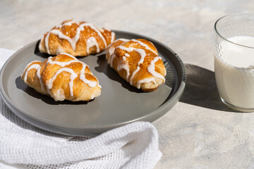 Tasty croissants with glass of milk on grey plate