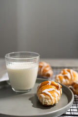 Croissants and glass of milk on a plate on a cooling rack on gray background