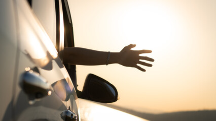 Hatchback Car travel driving road trip of man summer vacation in white car at sunset, happiness to travel, enjoy vacation and relax, male driver extends his hand out the car window while driving