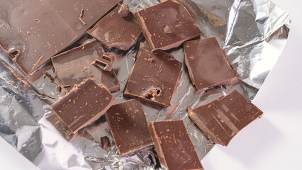 The chocolate bar is broken into pieces. Cocoa and chocolos on white background, concept of price...