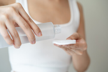 Close-up view hands of woman using toner and cotton pad to remove makeup