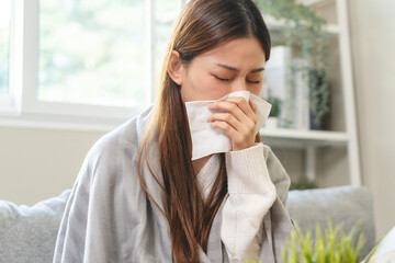 Seasonal sick concept. the young woman has a common cold and sneezing on the sofa.