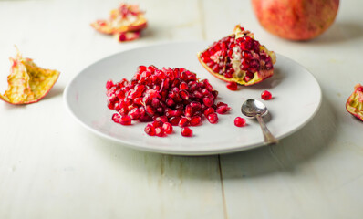 Red pomegranate seeds on white plate.