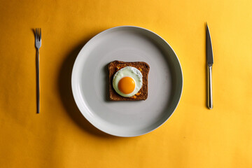 fried egg on a plate with fork and knife on the side