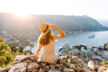 Young woman is looking at landscape of city from height. Travel in Europe. Back view.