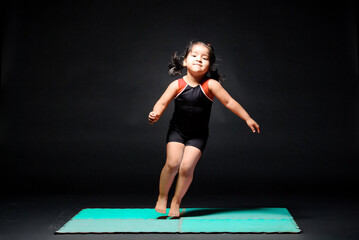 Beautiful Latin girl doing olympic gymnastics routines. The beautiful girl jumps to the left side of her with great joy.