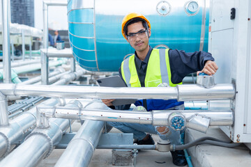 Engineer checks valves, water tanks, pumps and equipment related to hot water production pipe...