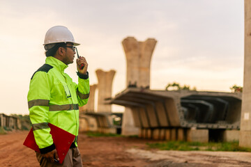 A man in a yellow jacket is writing on a clipboard while standing in front of a bridge. Concept of work and productivity