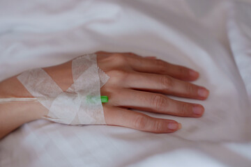 Patient's hand with an IV drip, on a clean white sheet, illustrating medical treatment and healing atmosphere in a hospital...