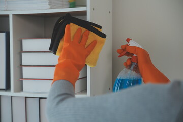Woman cleaning table using rag and diffuser at home.
