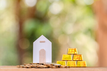 Home model put on the coin and stack gold bar with grow up to the interest put on the wood  in the public park, Loans for real estate or save money for buy a new house in the future concept.