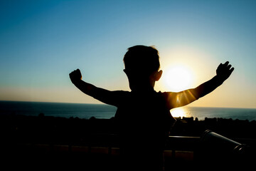Happy child at the time of the silhouette of the sea background