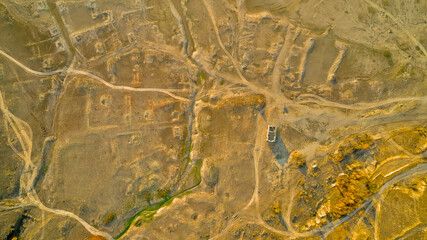 Traces of dirt roads and ruined houses mark the site of a former village, now submerged beneath the reservoir formed by a breached dam, with only the surviving church of St. Ivan Rilski, Bulgaria