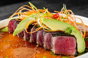 Exquisite gourmet dish featuring seared tuna slices, fresh avocado, and vibrant garnish, served in...