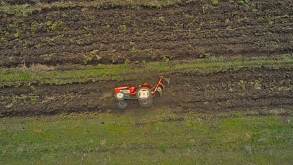 A tractor lying on its side in a plowed field, captured from above with a drone for aerial...