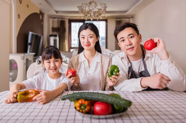 A family of three with vegetables at the table
