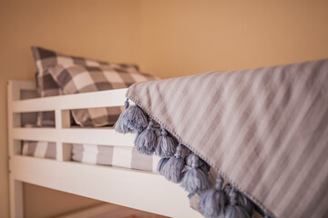 Grey stripe soft knit throw fringe tassels blankets stacked on a grey checkered bed sheet in a...