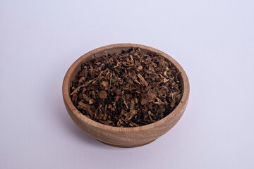 Tobacco granules in a wooden bowl on a white background. Tobacco in a brown wooden bowl.