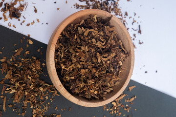 grains of knitted tobacco on a wooden bowl with isolated background. Traditional tobacco of...