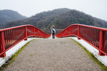 Man walking on Yume Tsuribashi, Red Suspension Bridge in Hiroshima, Japan - 日本 広島 夢吊橋...