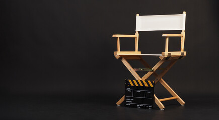 White director chair with yellow clapper board on black background.