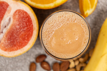 A citrus smoothie with grapefruit, banana and almond in a glass on a table