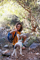 Little boy with a backpack on a hike. Healthy activity. a cheerful dog plays with a child during a hike, a child plays with a dog while trekking in the forest.