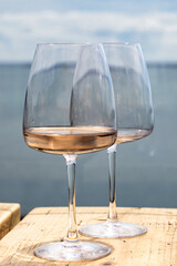 Two wine glasses on an outside table, with the sea behind