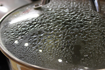Drops of hot condensation on the glass lid of a frying pan  
