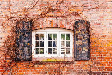 A rustic window set in an old brick wall adorned with creeping ivy in Oslo old city. Norway.