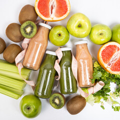 Healthy bottled smoothies among vegetables and fruits and measuring tape.