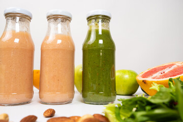 Different vegetable and fruit smoothies in glass bottles on white background.