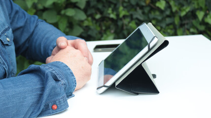 close-up of a man's hands holding his tablet in the garden