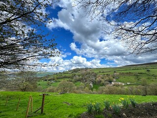 Picturesque landscape with rolling green hills beneath a dramatic sky, dotted with fluffy white clouds, set high upon the hills of Sutton-in-Craven, Keighley, UK.