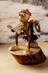 Funny Handicraft - a wooden little man, the head is made of acorns, reads a book made of birch bark...