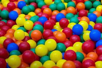 Colored plastic balls in pool of game room. Children's party, a games room, a box filled with small colored balls.