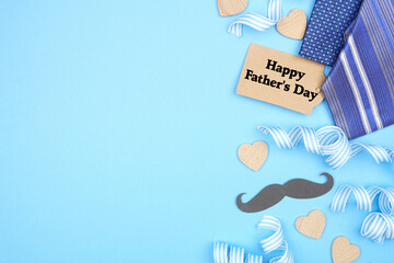 Happy Fathers Day gift tag with side border of gifts, decor, ties and ribbon. Top down view on a...