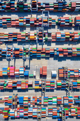 Aerial top down view of rows of cargo containers stacked up in a commercial harbour