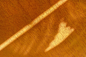 Background of orange colored rough cement wall and sunlight streaks on it.