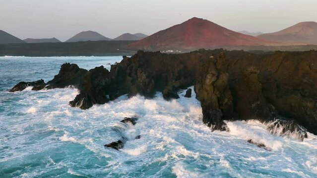aerial slow motion view of ocean and giant waves crashing at rocky cliff with splashing and white foam. Lanzarote. Canary islands, Spain