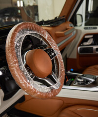 Macro shot of a steering wheel in a car with hood and automotive lighting